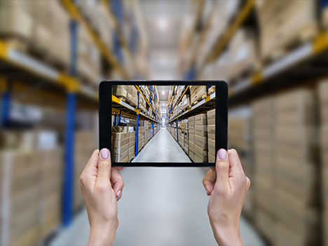Looking through a tablet at shelves in a warehouse